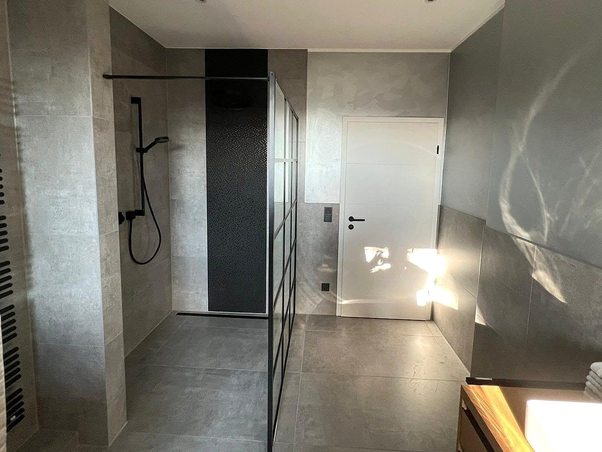 Walk-in-Dusche mit schwarzem Mosaikstreifen, Glaswand im Sprossen-Design und weißer Tür